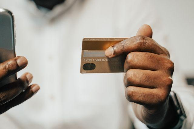 A person holding up a credit card and a phone